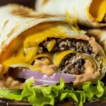 Air Fryer Cheeseburger Wraps with beef, cheese, onions, and sauce in a tortilla, served on a bed of lettuce.