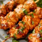 Close-up of Air Fryer Chicken Skewers garnished with herbs on a plate.