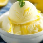 Ninja Creami Lemon Sorbet in a white bowl with a mint garnish, surrounded by fresh lemons.