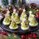 A festive black platter holds several christmas deviled eggs shaped like green Christmas trees with star toppers and colorful sprinkles.