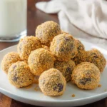 A plate piled high with sweet, crumb-coated no-bake moose farts, served alongside a refreshing glass of milk.