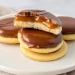A stack of homemade Twix Cookies with a rich caramel filling and smooth chocolate topping, one broken open to show the gooey center.
