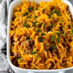 A hearty beef noodle casserole with egg noodles, savory ground beef, and a rich, creamy cheese sauce, garnished with parsley.