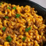 Savory Cheeseburger Macaroni in a cast iron skillet, with elbow pasta, ground beef, a rich cheesy sauce, and fresh parsley garnish.