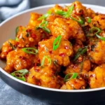 A close-up shot of a delicious Chili Chicken Recipe served in a bowl, garnished with fresh green onions and red chili flakes.