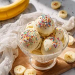 Scoops of delicious Ninja Creami Banana Cinnamon Ice Cream, topped with colorful sprinkles, served in a glass bowl with fresh bananas.