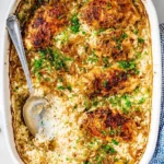 A close-up of a delicious no peek chicken casserole in a white baking dish with perfectly cooked rice, browned chicken, and caramelized onions, garnished with fresh herbs.