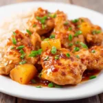 Delicious Crockpot Hawaiian Chicken with pineapple and a sweet chili glaze, garnished with green onions and served with rice.