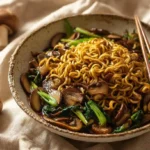 A close-up shows a bowl of mushroom ramen noodles with sliced mushrooms, green vegetables, and chopsticks, surrounded by fresh whole mushrooms.