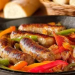 A cast iron skillet filled with perfectly browned Sausage and Peppers, featuring green, red, and orange bell peppers.