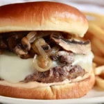 A savory Swiss Mushroom Melt sandwich with melted cheese, sautéed mushrooms, caramelized onions, and golden fries.
