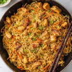 A large pan filled with delicious Thai Peanut Sauce Noodles with Chicken, garnished with green onions and sesame seeds.