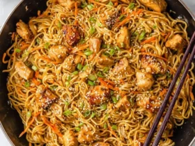 A large pan filled with delicious Thai Peanut Sauce Noodles with Chicken, garnished with green onions and sesame seeds.