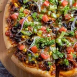 A vibrant Vegetarian Black Bean Pizza, loaded with corn, tomatoes, olives, onions, and fresh herbs, served on a wooden board.
