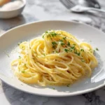 Close-up of a perfectly plated serving of savory butter noodles, sprinkled with fresh parsley and grated Parmesan cheese.