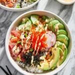 Two vibrant California Sushi Bowls with fresh salmon, tuna, avocado, cucumber, radish, tobiko, and sauce on a marble surface.