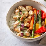 A delicious Chicken and Roasted Vegetable Bowls with rice, tender chicken, carrots, asparagus, and bell peppers.