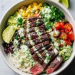Vibrant Cilantro lime steak bowls with grilled steak, rice, black beans, corn, guacamole, cherry tomatoes, and lime wedges.