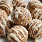 Close-up of several delicious cinnamon roll protein bites covered in white glaze on a white plate.