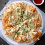 A delicious Crab Rangoon Pizza, cut into many slices, topped with shredded crab, orange sauce drizzles, and green onions, served with a side of dipping sauce.
