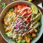 A vibrant overhead shot of delicious Fish Taco Bowls featuring seasoned fish, rice, corn, pico de gallo, avocado, and lime wedges.