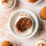 Overhead view of various homemade Gingerbread Truffles, including white chocolate-coated with crumbs and cocoa-dusted, with one bitten.