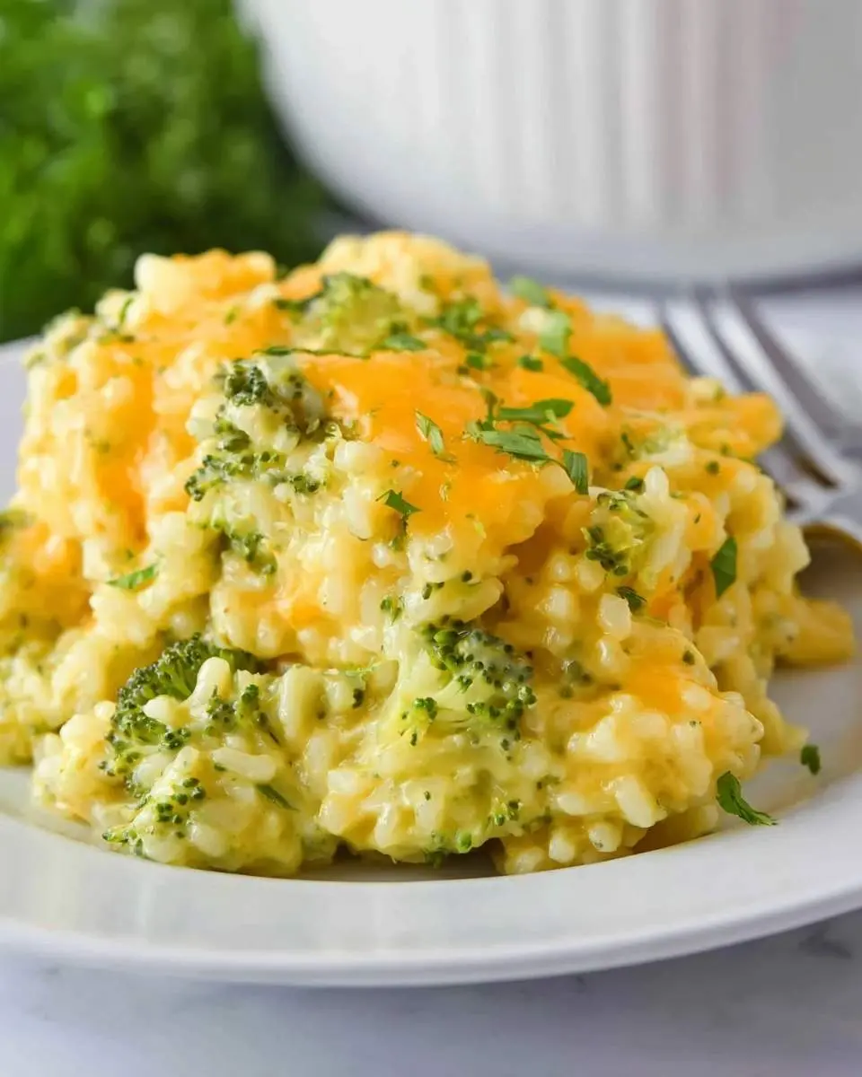 Velveeta Broccoli Rice Casserole 25 A close-up shot of a creamy and cheesy Velveeta Broccoli Rice Casserole on a white plate, garnished with fresh parsley.