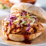 A mouthwatering BBQ Pulled Chicken Sandwich with Coleslaw, featuring shredded chicken in tangy sauce and colorful slaw on a rustic bun.