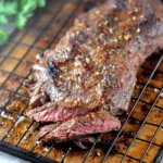 A perfectly cooked and sliced Dutch Oven Skirt Steak resting on a wire rack, revealing a juicy, medium-rare interior, seasoned with spices.