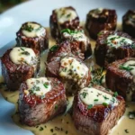 A plate of perfectly seared Garlic Butter Steak Bites with Creamy Parmesan Sauce, garnished with fresh herbs.