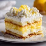A delectable slice of Lemon Lush Lasagna, featuring layers of cake, creamy white filling, bright lemon curd, and topped with whipped cream and lemon zest.
