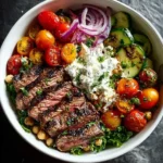 A vibrant mediterranean grilled steak bowl featuring sliced steak, roasted tomatoes, cucumbers, red onions, feta dip, and chickpeas.