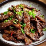 A close-up of delicious Beef Bulgogi garnished with fresh green onions and toasted sesame seeds in a rustic bowl.
