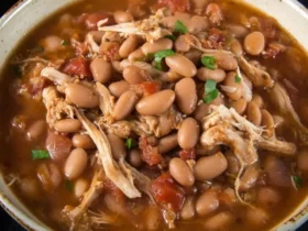 A hearty bowl of Jalapeño Beans with Shredded Chicken, garnished with fresh herbs, served on a dark background.