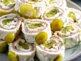 A close-up of delicious Pickle Dip Pinwheels arranged on a plate, garnished with fresh dill and pickle slices.