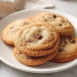 A plate filled with delicious golden-brown sourdough discard cookies, featuring melty chocolate chips on top.