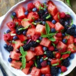 Fresh Watermelon Berry Salad with cubed watermelon, blackberries, blueberries, and raspberries garnished with mint in a white bowl.