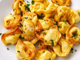 Air Fryer Tortellini 52 Golden crispy Air Fryer Tortellini served on a white plate, garnished with fresh herbs and grated cheese.