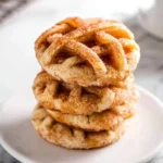 Stack of three cinnamon-sugar Apple Pie Cookies on a white plate with marble background.