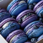 Close-up of Blueberry Lemonade Macarons in purple and blue ombre shells with fresh blueberries and speckled filling.