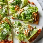 Sliced Chicken Caesar Salad Pizza topped with fresh romaine lettuce, creamy dressing, and croutons on a crispy crust.