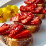 Chocolate Strawberry Bruschetta with fresh strawberry slices on toasted bread, garnished with edible flowers.