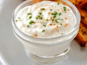 garlic aioli sauce 49 Creamy garlic aioli sauce in a glass bowl garnished with chives and paprika, served with toasted bread.