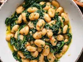 A white bowl filled with Garlic Butter Beans with Spinach, topped with grated cheese and red pepper flakes.