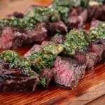 Sliced Grilled Hanger Steak with Chimichurri sauce on a wooden cutting board.