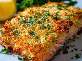 Golden Parmesan Crusted Baked Salmon fillet topped with crispy breadcrumbs and fresh herbs on a white plate.