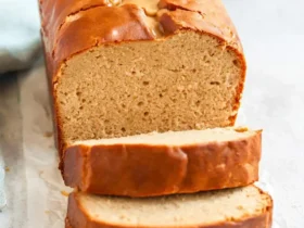 Peanut Butter Bread 55 A freshly baked loaf of peanut butter bread with three slices cut and stacked in front, showing a soft, moist crumb.