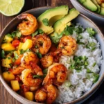 Delicious shrimp and rice bowls with grilled shrimp, white rice, avocado slices, and fresh mango salsa in a ceramic bowl.