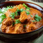 Slow Cooker Chicken Tikka Masala served in a brown bowl with rice and fresh cilantro garnish.