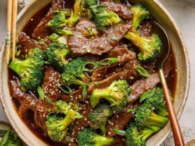 Teriyaki Beef and Broccoli 52 A bowl of Teriyaki Beef and Broccoli with tender beef slices and vibrant green broccoli in a glossy sauce, topped with sesame seeds and green onions.